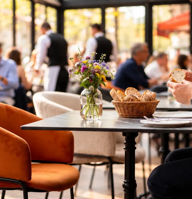 24 juin (9) Temps d’attente au restaurant dans une salle lumineuse avec des fauteuils orange et des clients installés à table.